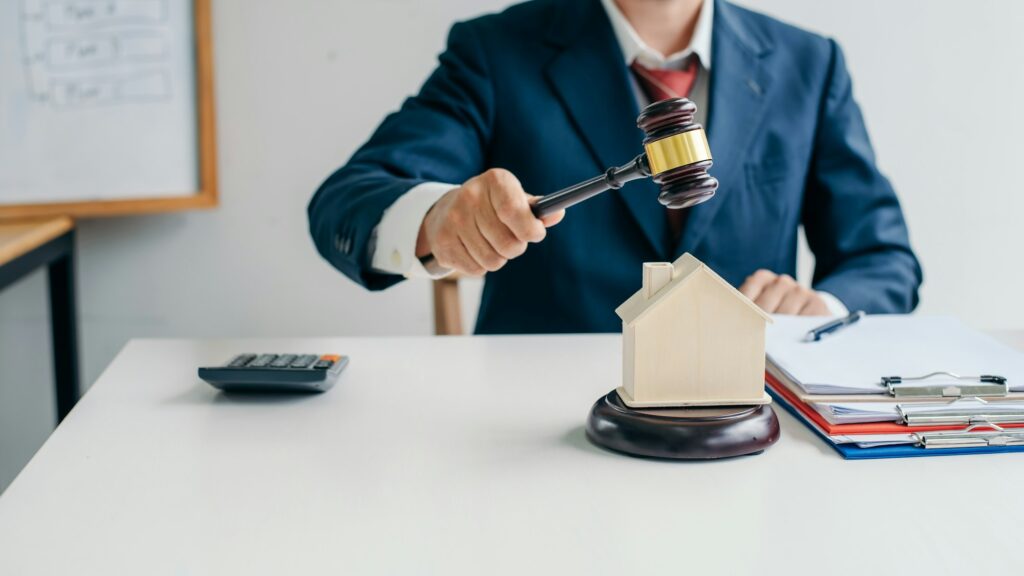 Image of lawyer holding a auction hammer on model house. Concept of the law is to buy or sell houses